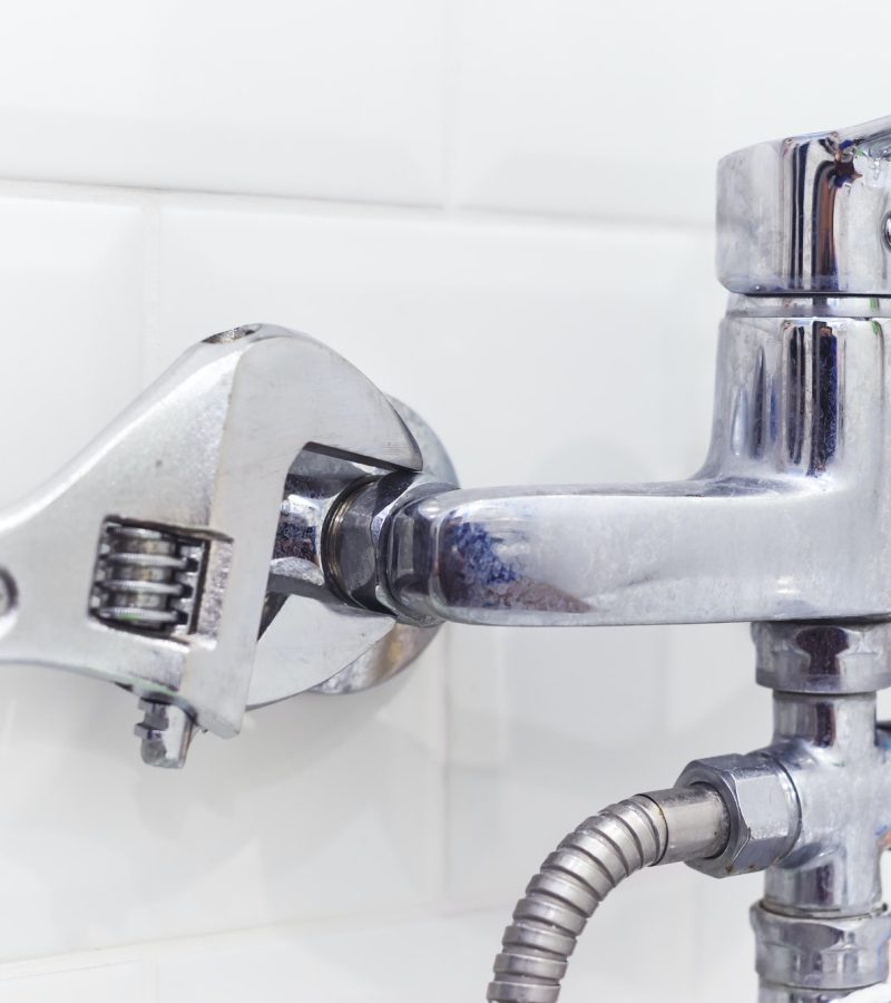plumber uses pipe wrench for service shower mixer tap